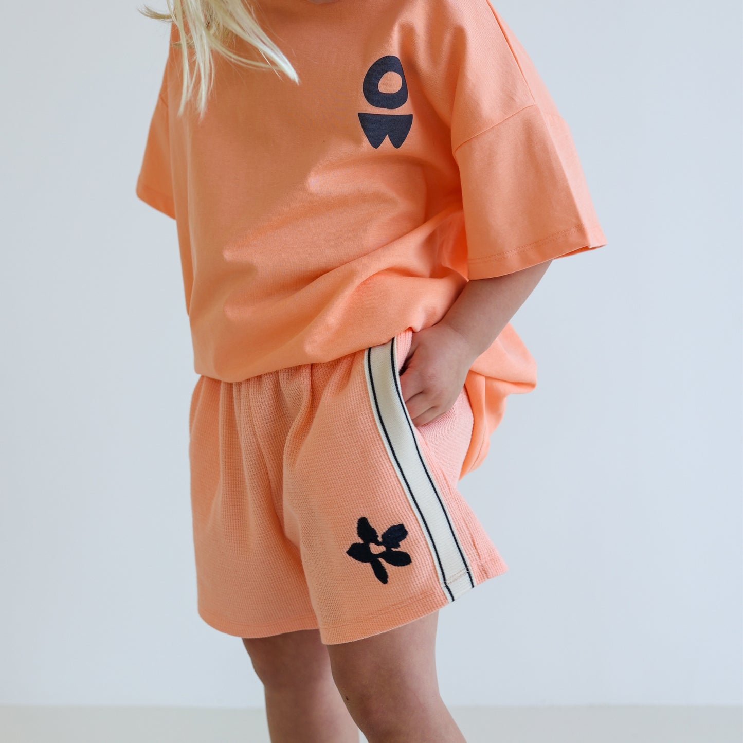 Children’s organic cotton Waffle Short by OLLE, with contrast side seam tape, embroidery, and relaxed shorter fit