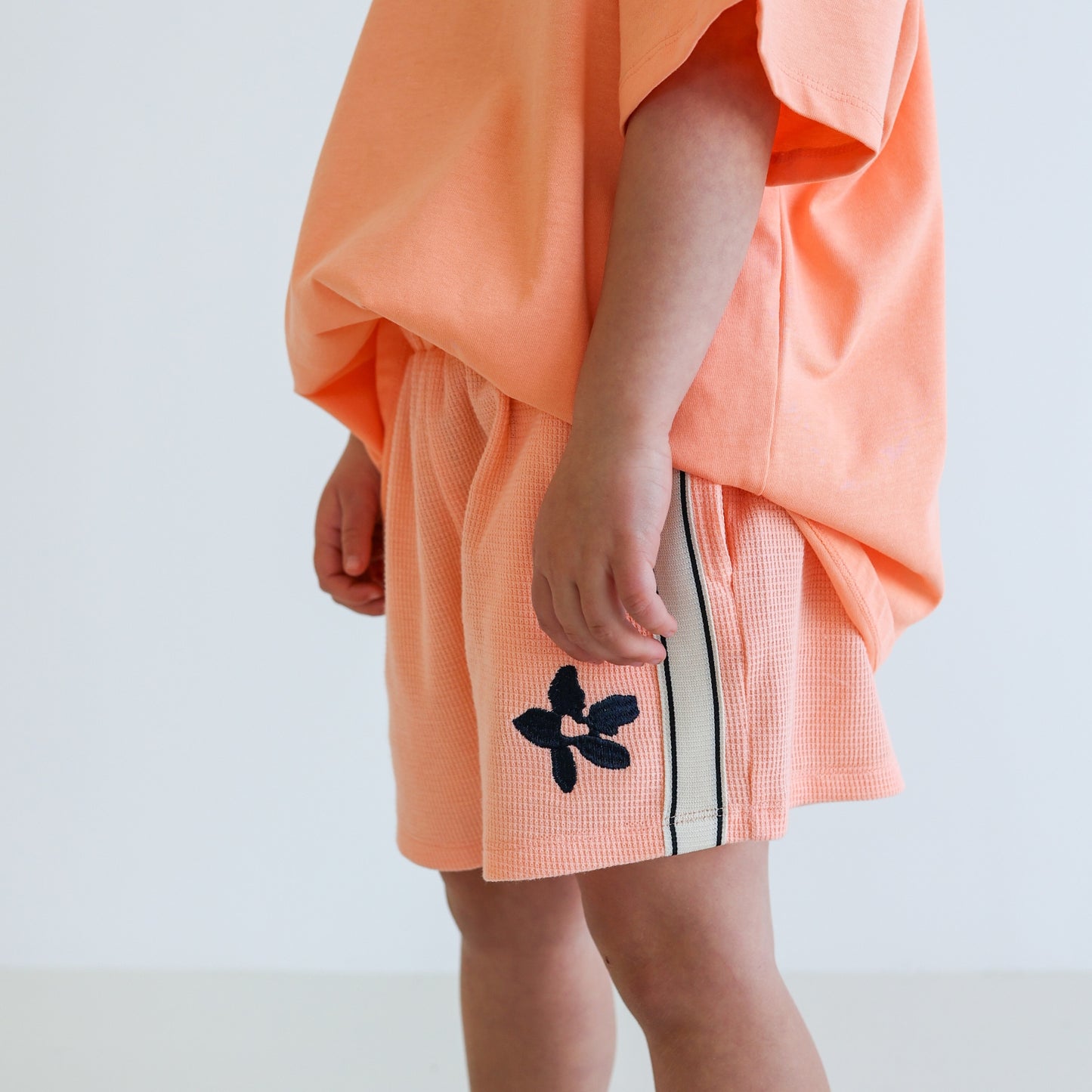 Children’s organic cotton Waffle Short by OLLE, with contrast side seam tape, embroidery, and relaxed shorter fit