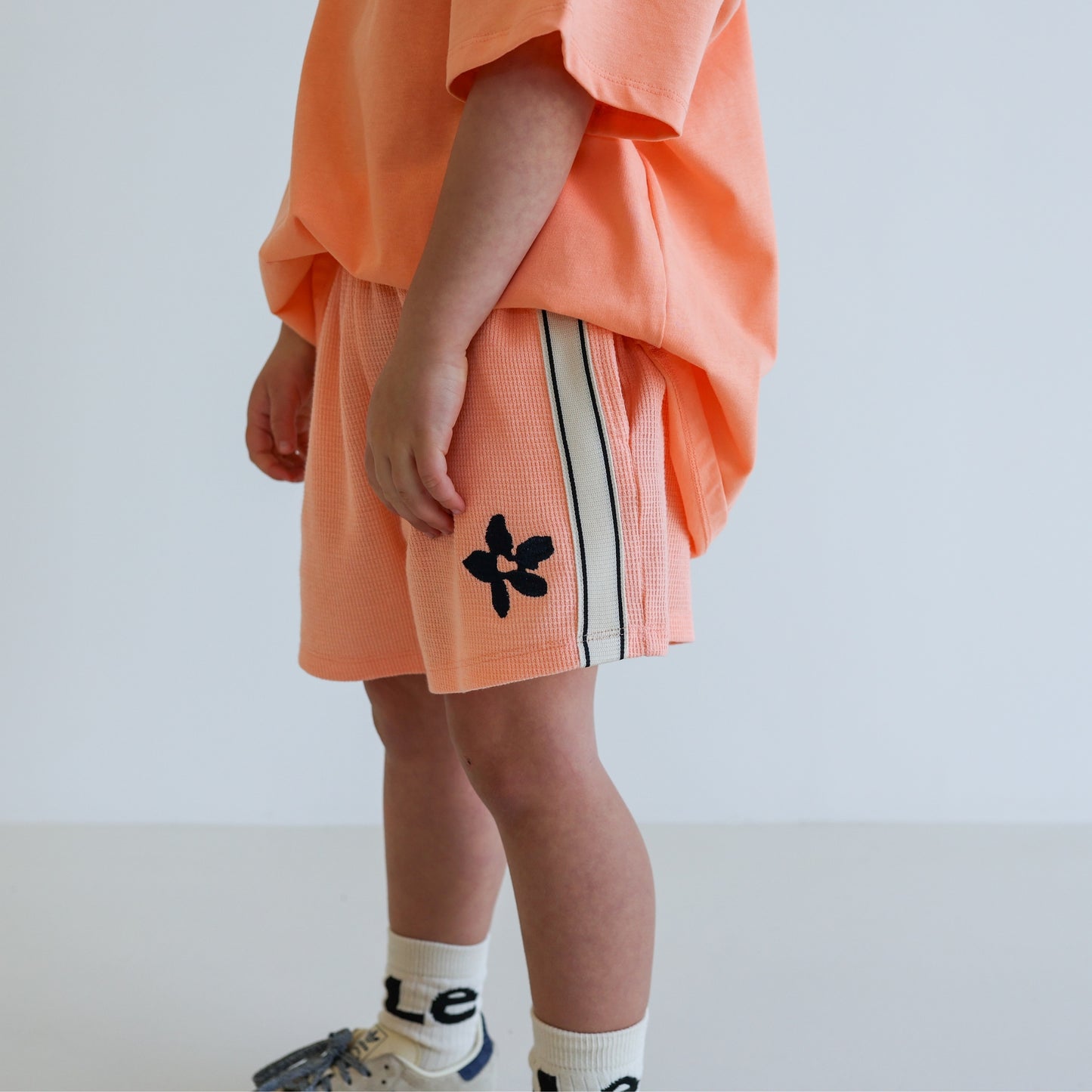 Children’s organic cotton Waffle Short by OLLE, with contrast side seam tape, embroidery, and relaxed shorter fit