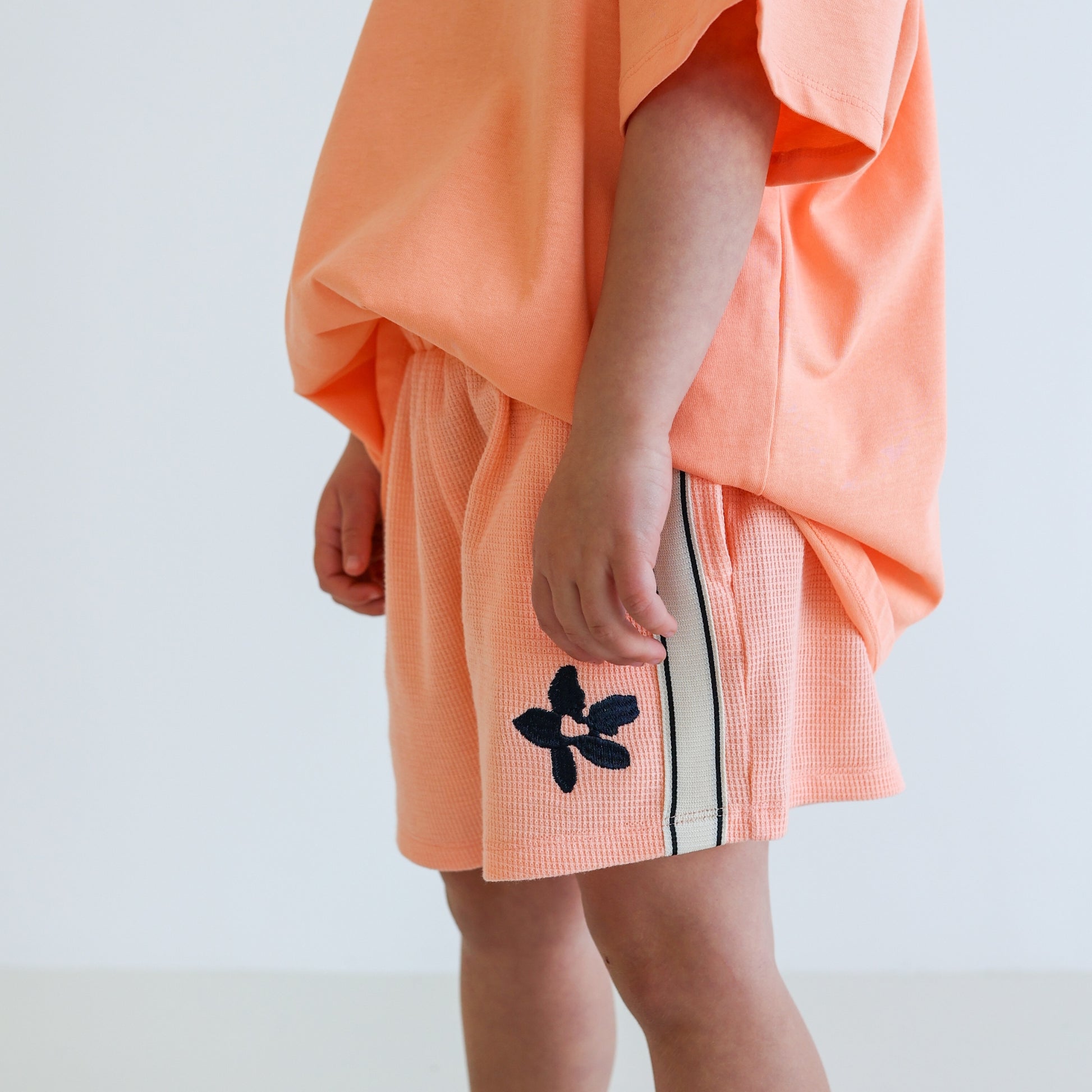 Children’s organic cotton Waffle Short by OLLE, with contrast side seam tape, embroidery, and relaxed shorter fit