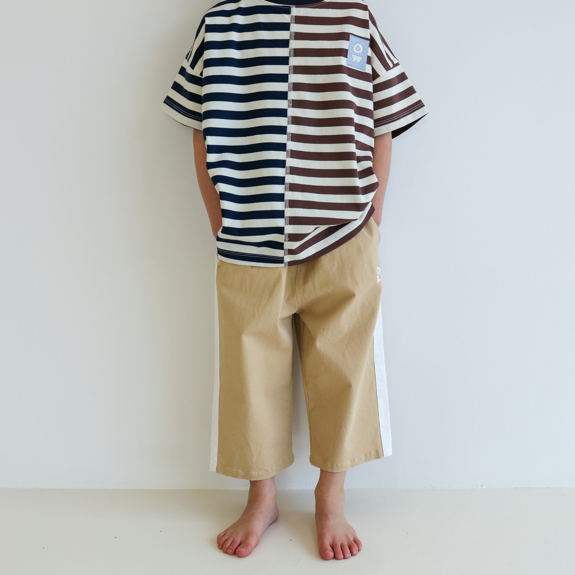 Children’s oversized organic cotton Split Stripes Tee by OLLE, with yarn-dyed stripe panels, contrast stitch, and chest embroidery.